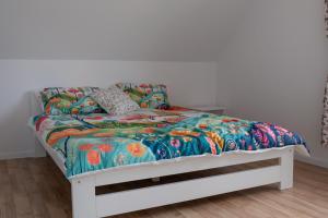 a bed with a colorful comforter and pillows on it at Mese Szálló in Lăzarea