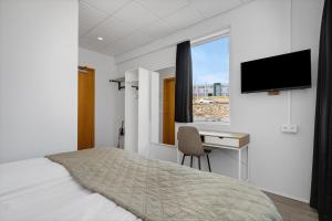 a bedroom with a bed and a desk and a television at ASKA Heiðmörk in Reykjavík