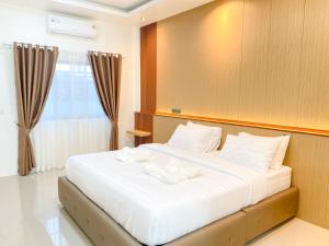 a bedroom with a bed with white sheets and a window at Aten hotel in Sathani Khao Pip