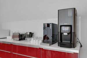 a kitchen with a counter top with a coffee maker and a refrigerator at ASKA Heiðmörk in Reykjavík +21 photos