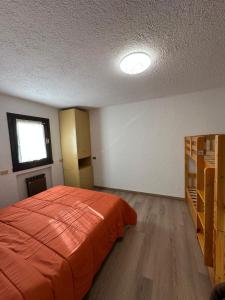 a bedroom with an orange bed and a window at Piazzetta Montecampione in Pian Camuno