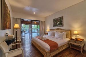 a bedroom with a bed and a desk and a chair at Miko Villas Ubud in Ubud
