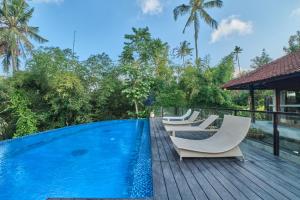 a swimming pool with lounge chairs on a wooden deck at Miko Villas Ubud in Ubud