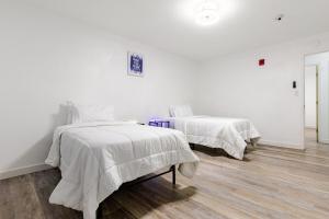 two beds in a room with white walls and wood floors at The Chautard Suite in Pueblo