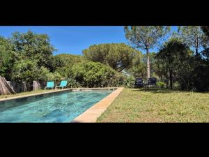 a swimming pool with two blue chairs in a yard at Villa Spa privé golf in Servian