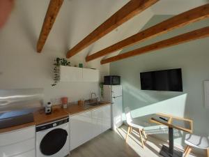 a kitchen with white cabinets and a table and a tv at Rever la Saône in Rigny