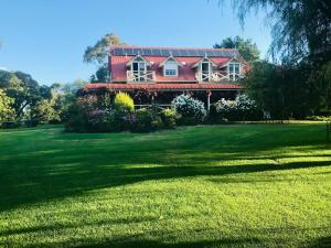 a house with a red roof on a green field at Hawk's Nest Bed & Breakfast in Bathurst