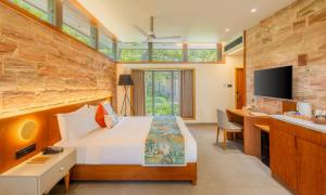 a bedroom with a bed and a desk and a television at The Forest Chapter by Sayaji Sasan Gir in Chitrod