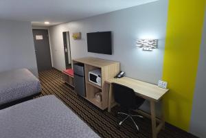 a hotel room with a bed and a desk with a television at Super 8 by Wyndham Yankton in Yankton