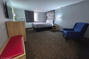 a hotel room with a bed and a blue chair at Super 8 by Wyndham Yankton in Yankton