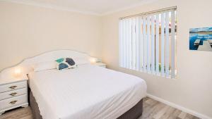 a white bedroom with a bed and a window at Studio 66 Busselton in Busselton