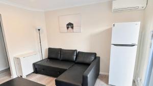 a black leather couch in a living room with a refrigerator at Studio 66 Busselton in Busselton