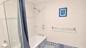 a bathroom with a shower and a tub and a sink at Studio 66 Busselton in Busselton