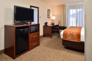 a hotel room with a bed and a flat screen tv at Comfort Inn & Suites Madison North in De Forest