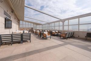 a rooftop patio with chairs and tables and windows at Weekend Hotel Sari in Jeddah