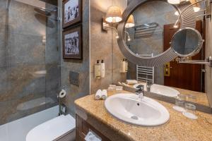 ein Badezimmer mit Waschbecken, Spiegel und Badewanne in der Unterkunft Hotel Golden Eagle in Levice