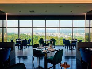 a restaurant with tables and chairs and large windows at DoubleTree By Hilton Seoul Pangyo in Seongnam