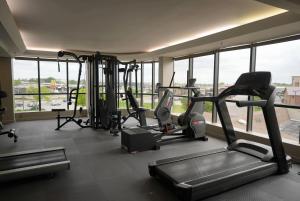 a gym with cardio equipment in a building with windows at Ramada by Wyndham Tulsa Broken Arrow in Broken Arrow