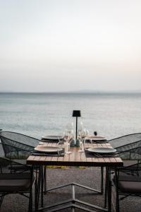 a wooden table with wine glasses on the beach at Vincci EverEden in Anavyssos +93 photos