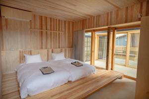 a bedroom with a white bed with two books on it at ホテル聚 - Hotel SHU in Tonosho