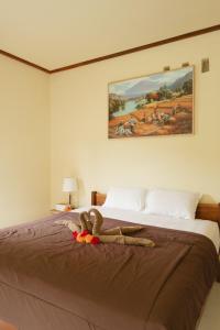 a bedroom with a large bed with a painting on the wall at Santika Guest House in Ubud