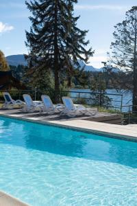 a swimming pool with lounge chairs and a lake at Charming Residences & Suites with Private Spa in San Carlos de Bariloche