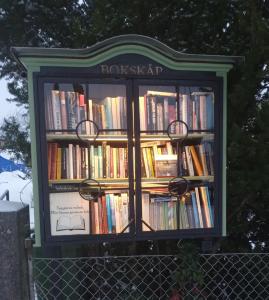 a book shelf filled with books on top of a fence at Villagatan in Hjo