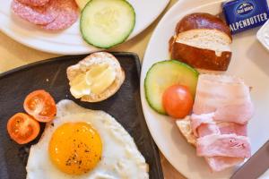 a plate of breakfast food with an egg and bread at Berghotel Almrausch in Berwang +50 photos