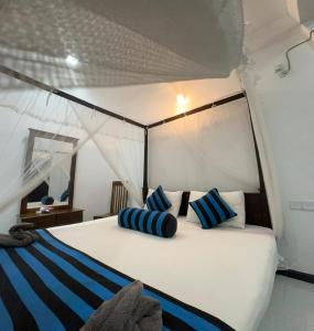 a bedroom with a bed with blue and white pillows at Sigiriya Danu Homestay in Sigiriya