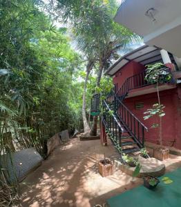 a red building with a staircase next to some trees at Sigiriya Danu Homestay in Sigiriya