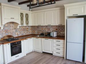 a kitchen with white cabinets and a white refrigerator at Dolon Hostel in Bishkek