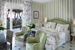 1 dormitorio con 1 cama y 2 sillas verdes en Cala del Porto Resort, en Punta Ala