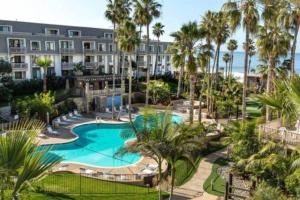 an aerial view of a resort with a pool and palm trees at SolMar Breeze - 1BR Condo at North Coast Village - Heated Pools, Hot Tubs & Steps to Beach, Oceanside Harbor and Pier in Oceanside