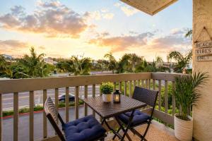 a table and chairs on a balcony with a view of a street at SolMar Breeze - 1BR Condo at North Coast Village - Heated Pools, Hot Tubs & Steps to Beach, Oceanside Harbor and Pier in Oceanside