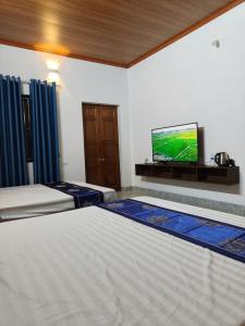 a bedroom with two beds and a flat screen tv at Senna Garden Homestay in Xuân Sơn