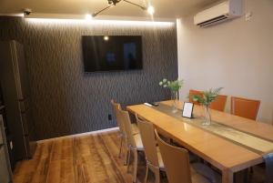 a dining room with a table and a television on a wall at Stella Casa in Gotemba +2 photos