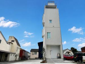 a white tower with a car parked next to it at 塔の宿 宍道湖 in Matsue