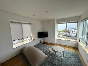 a living room with a couch and a table and two windows at 塔の宿 宍道湖 in Matsue