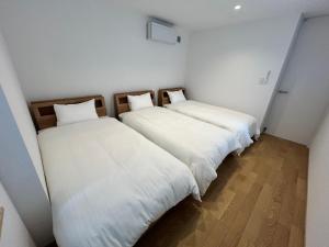 two beds in a room with white walls and wooden floors at 塔の宿 宍道湖 in Matsue