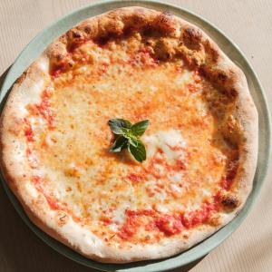 a cheese pizza with a green leaf on top of it at Hotel Goldenes Roessl-adults only in Bressanone