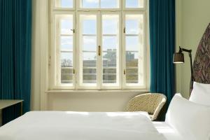 a bedroom with a bed and a window and a chair at The Cloud One Wien-Staatsoper in Vienna