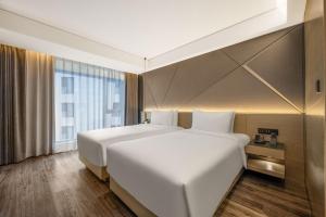 a bedroom with two white beds and a large window at Mercure Harbin Central Street Sophia Church in Harbin +55 photos