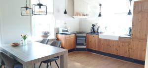a kitchen with wooden cabinets and a table with chairs at Gastenverblijf Boerengeluk in Gersloot