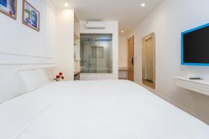 a white bedroom with a large bed and a flat screen tv at HUB MULTI 3 HOTEL - Sea & Firework View in Phú Quốc