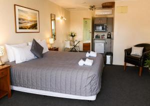 a bedroom with a large bed and a kitchen at Aspen on King in Timaru