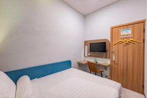 a bedroom with a bed and a desk and a tv at Front One Budget Hotel Tirtonadi Solo in Solo