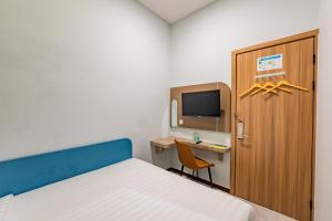 a bedroom with a bed and a desk and a tv at Front One Budget Hotel Tirtonadi Solo in Solo +14 photos