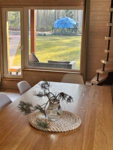 a vase on a plate on a table with a window at ForrestVila in Karačiūnai