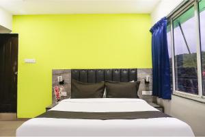 a bedroom with a large bed with a yellow wall at FabHotel Vardhan Plaza in Pune