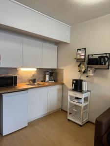 a kitchen with white cabinets and a counter top at Hotelli Terme 111 in Kilvakkala